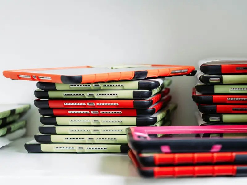 Stacks of iPads and tablets in protective cases awaiting repair